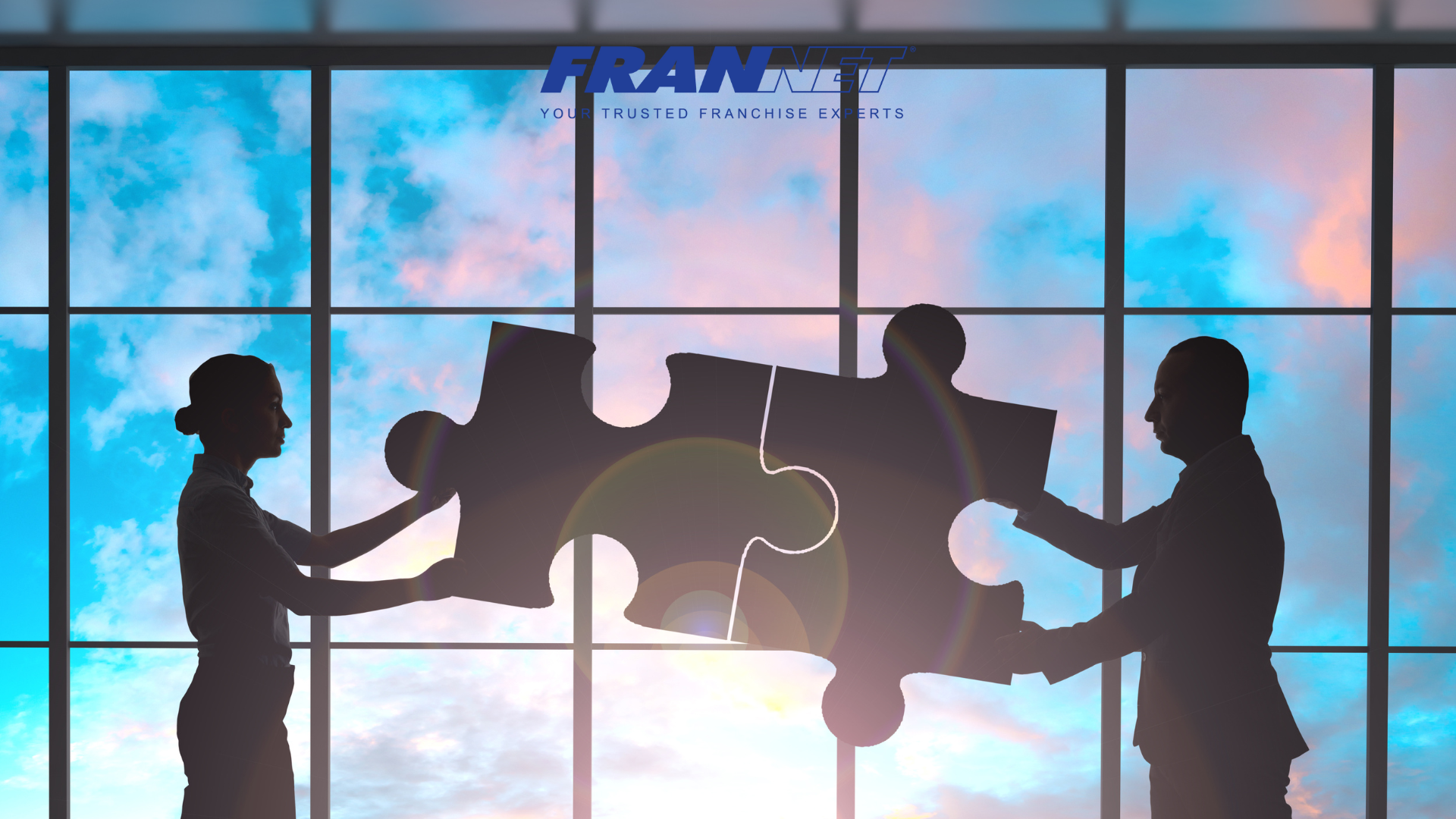 Two people each holding a giant puzzle piece that fits together