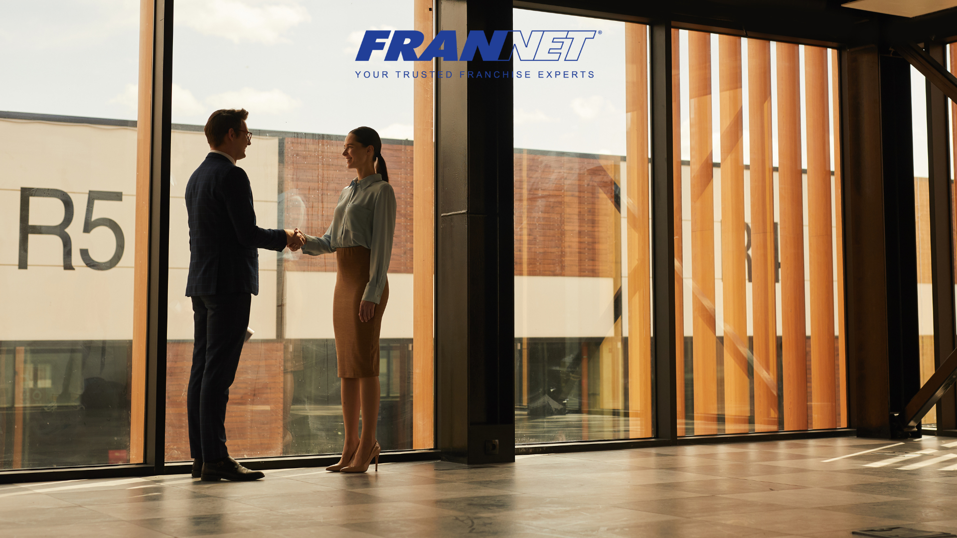 Two people shaking hands in empty office space