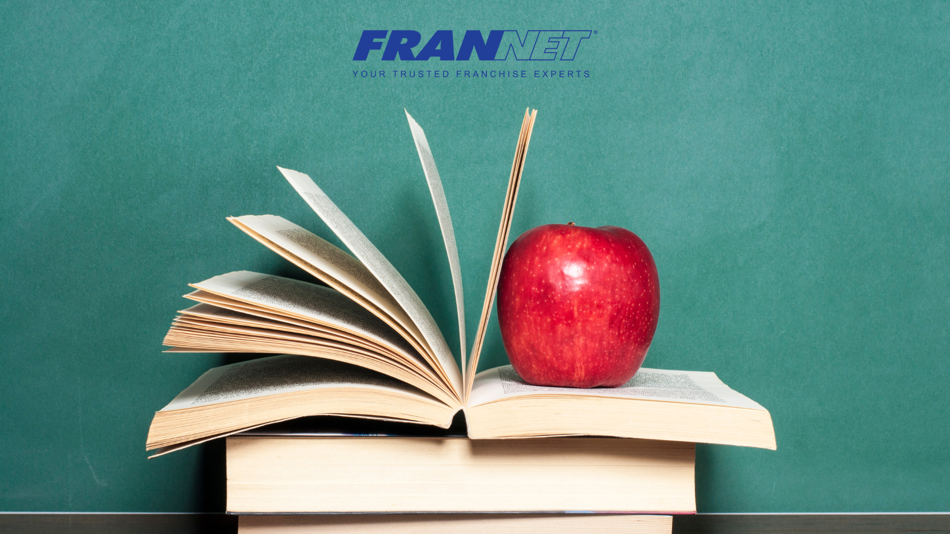 A stack of books with an apple on top of an open book
