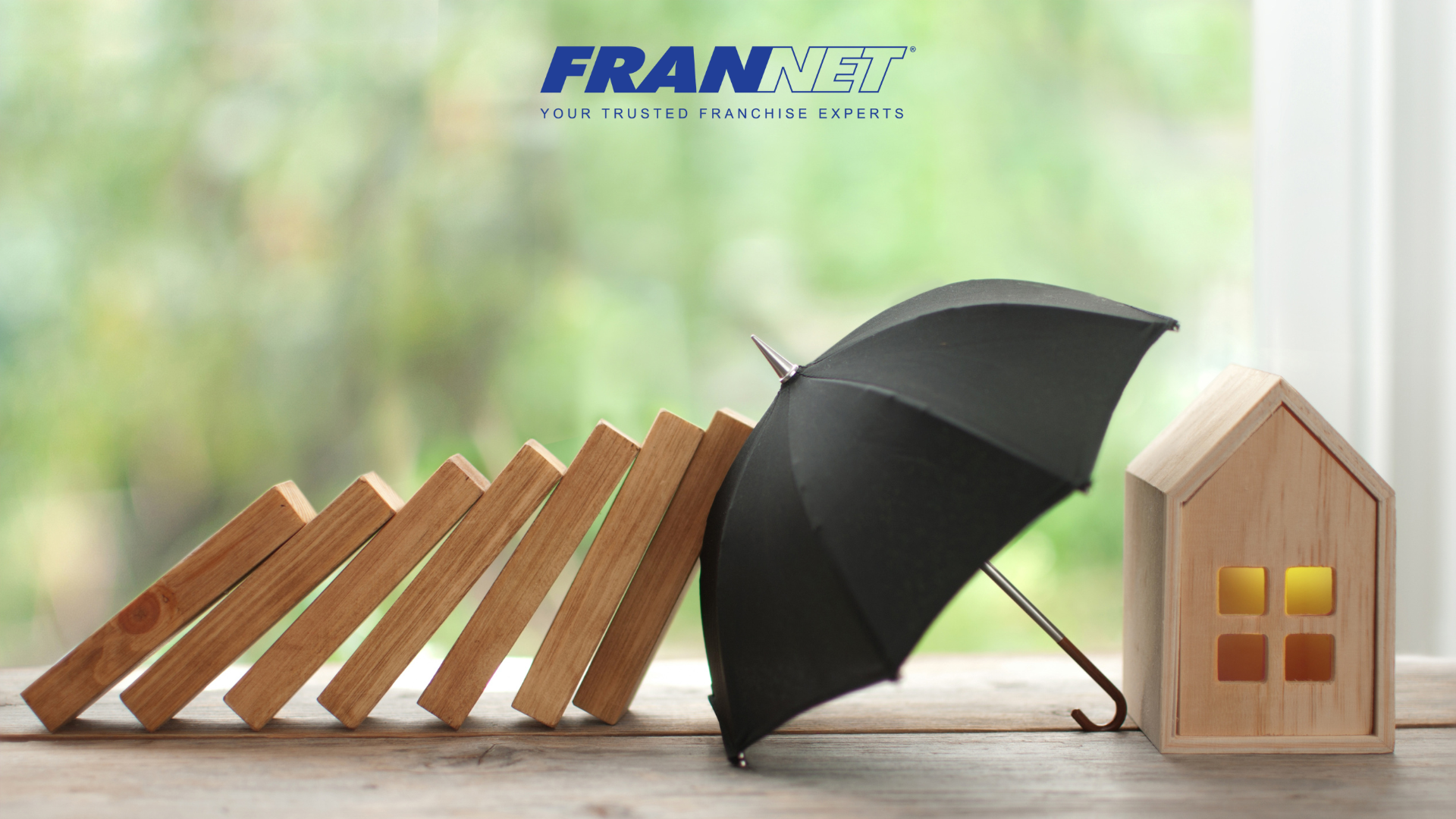 Umbrella protecting house from other wooden blocks falling over