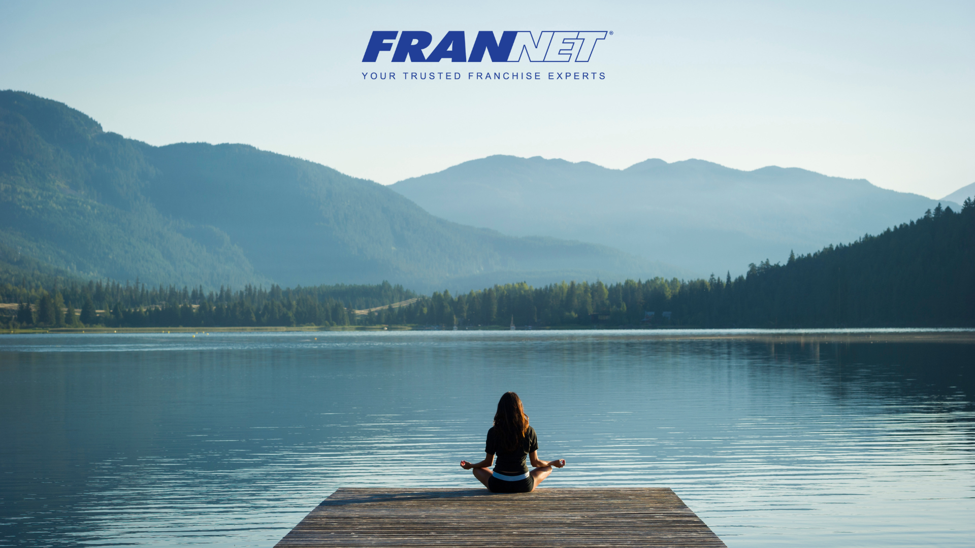 Person sitting in yoga position at the end up the pier with scenic landscape