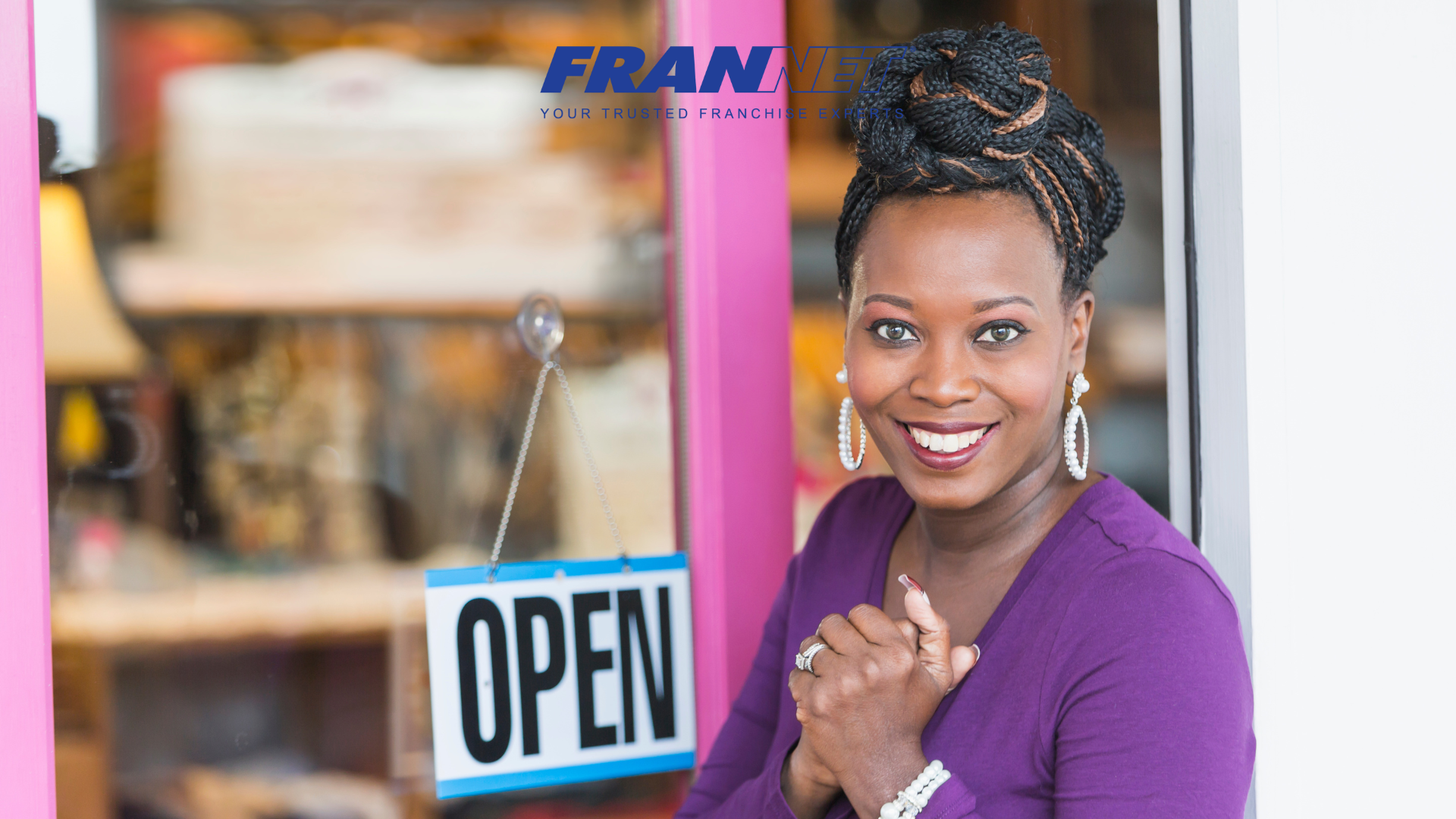 Woman smiling excitedly in front of "open" sign